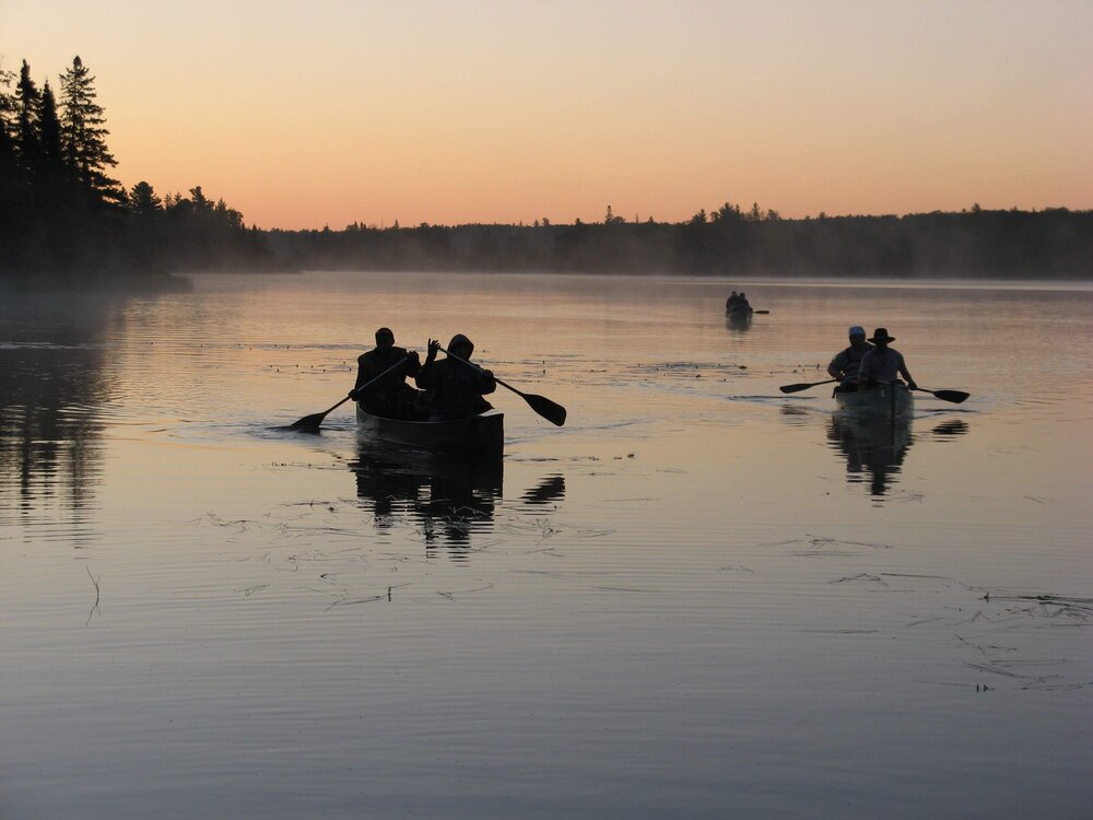 Three canoes and paddlers at dawn in the BWCA