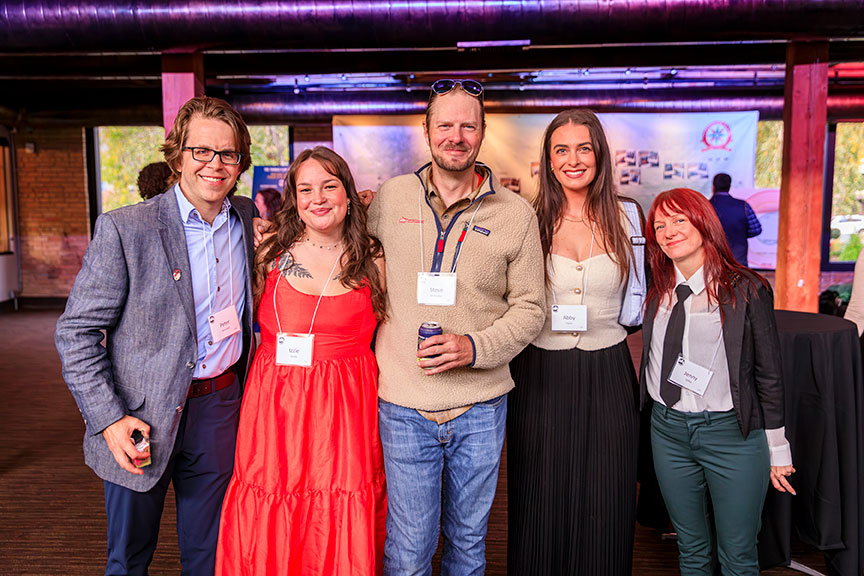 Five smiling gala attendees pose in front of a Boundary Waters map