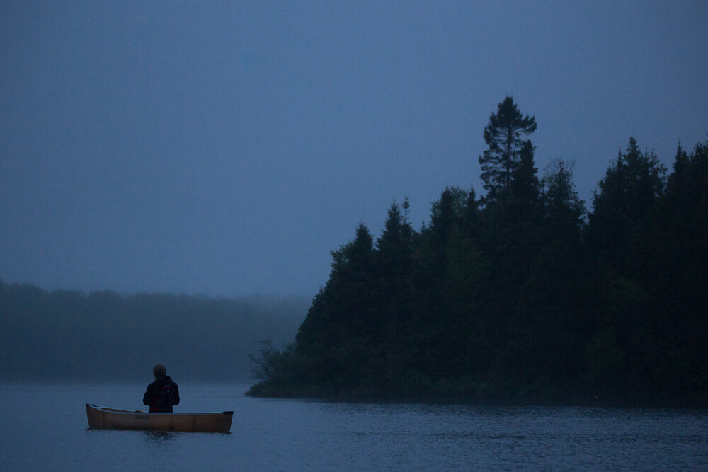 Solo canoe at dusk on a lake in the Boundary Waters.