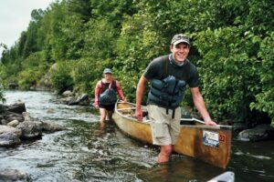 Paddlers guiding a canoe through a shallow river in the BWCA