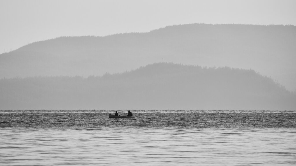 Fishermen in a canoe, in front of foggy hillsides in the Boundary Waters