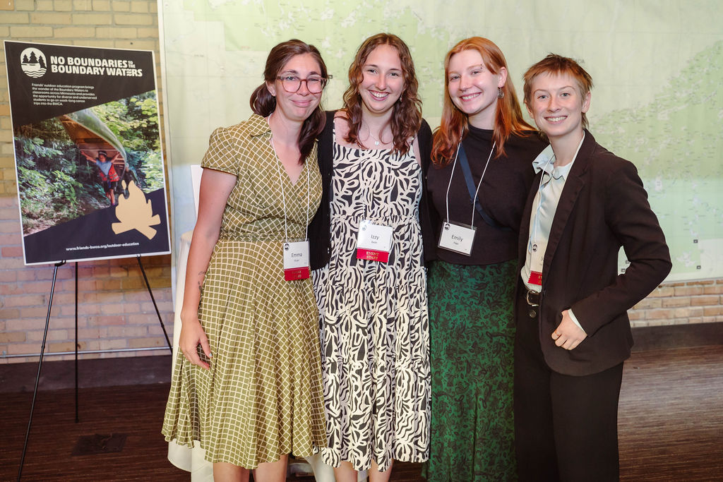 A group of Gala attendees smiling in front of signs and maps.