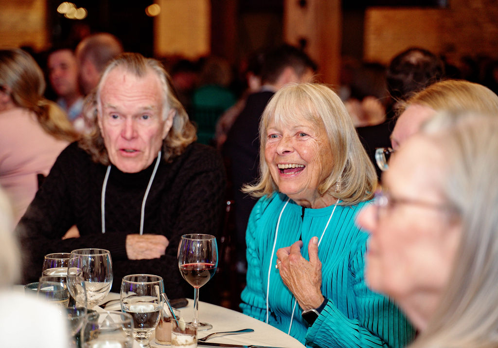 A man and a woman smiling and laughing at a table.
