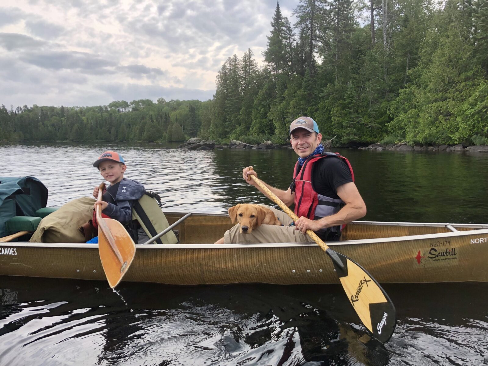 Photo Emily Fibeger A kid and adult sitting in a canoe, paddling in the Boundary Waters