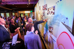 Man pointing at a BWCA map at an event with people milling around