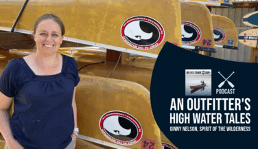 Outfitter Ginny Nelson stands next to a rack of canoes.