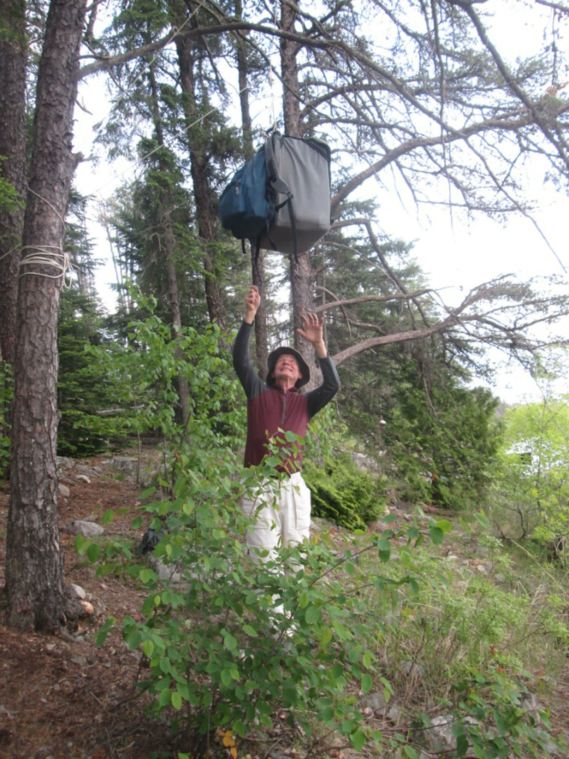 Image of a man in the Boundary Waters hanging a line for his gear.