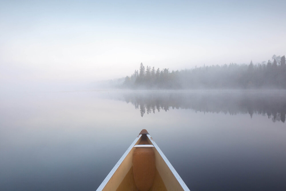 Bow of a canoe on a misty BWCA lake