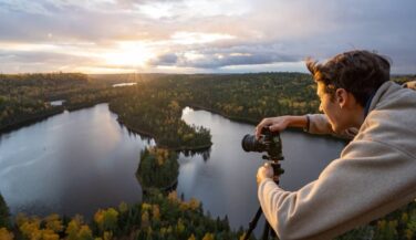 A person pointing a camera at scenic Boundary Waters overlook