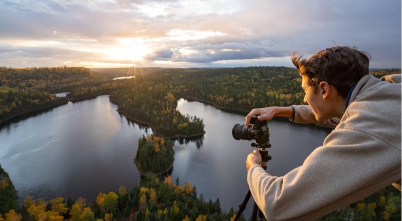 A person pointing a camera at scenic Boundary Waters overlook