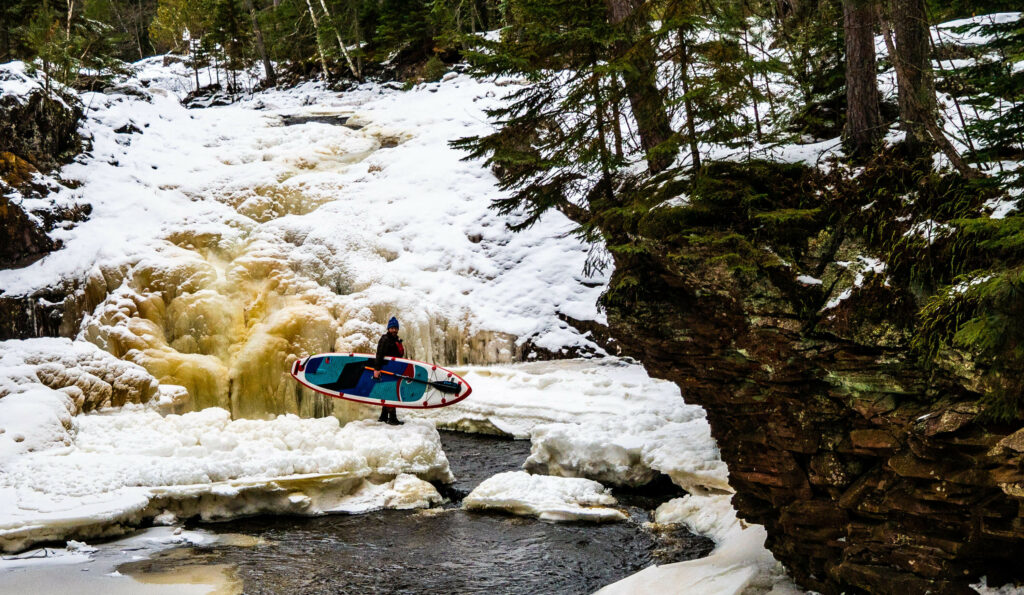 Image of a man portaging his stand up paddle board.