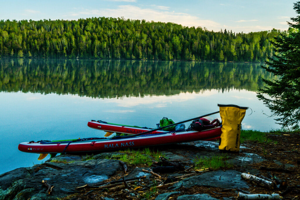 Image of two stand up paddle boards resting on the shores of the Boundary Waters.