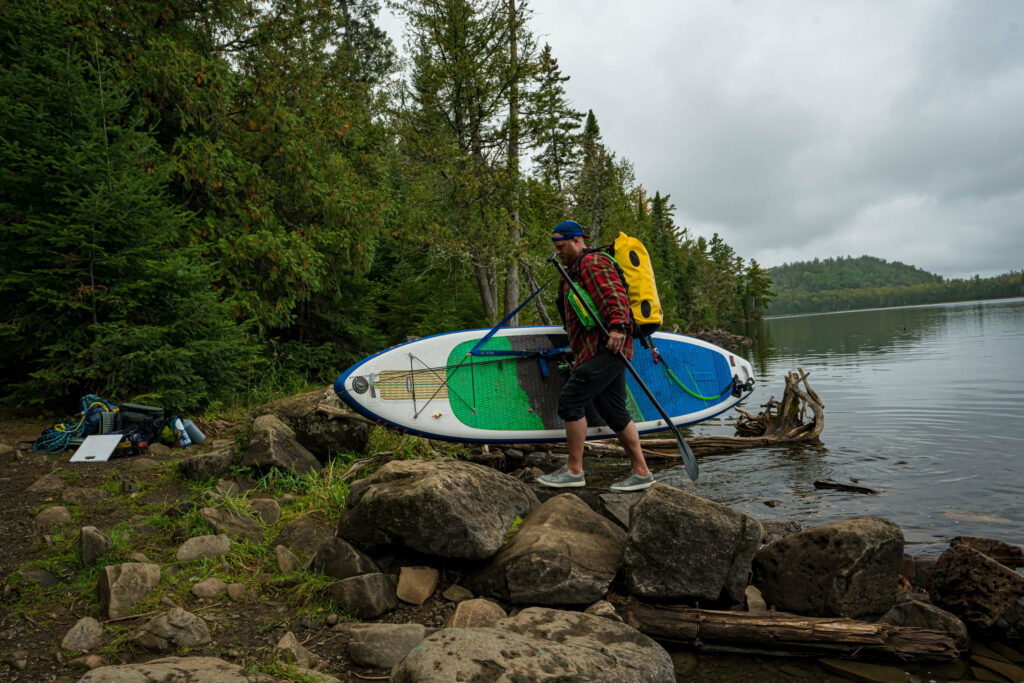 Image of a man portaging his stand up paddle board in Boundary Waters