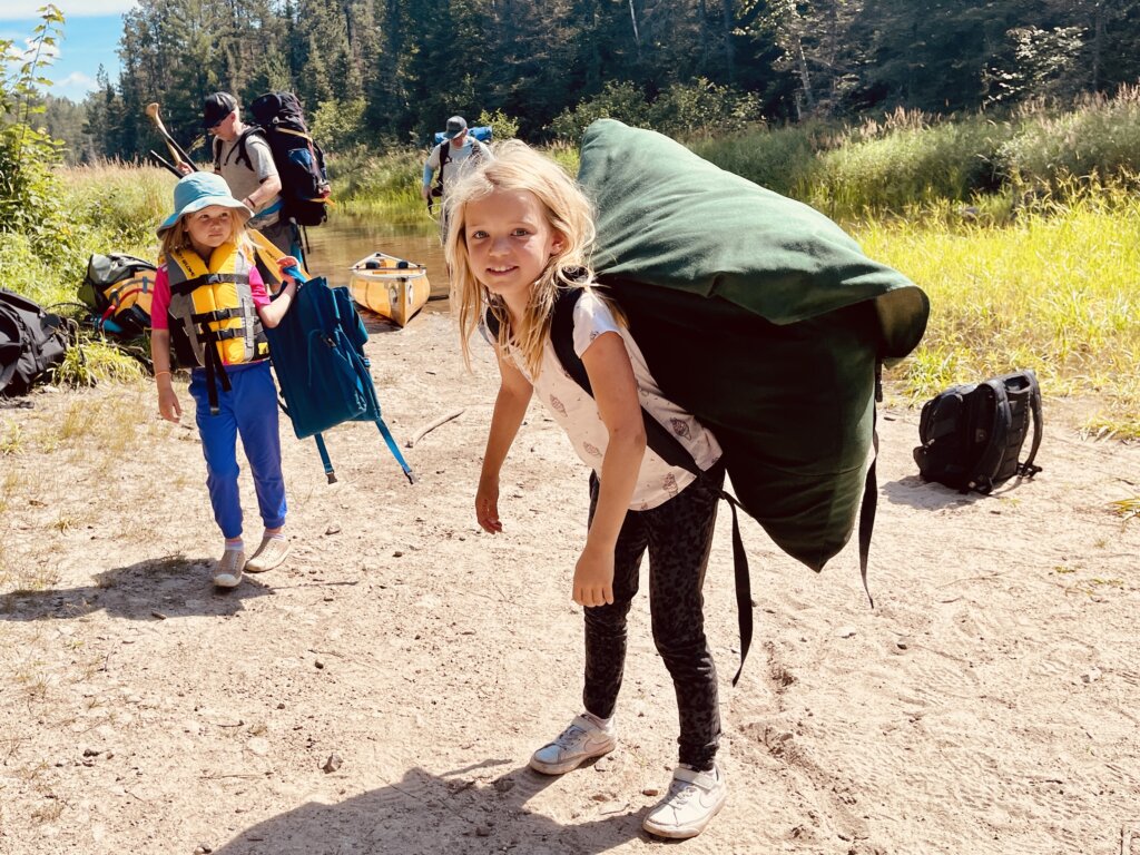 A girl standing on a portage with a large Duluth pack in the Boundary Waters.