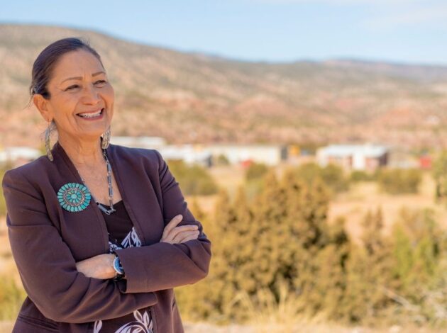 Deb Haaland smiling in front of a natural landscape