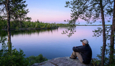 Man looking over a lake from a campsite in the Boundary Waters.
