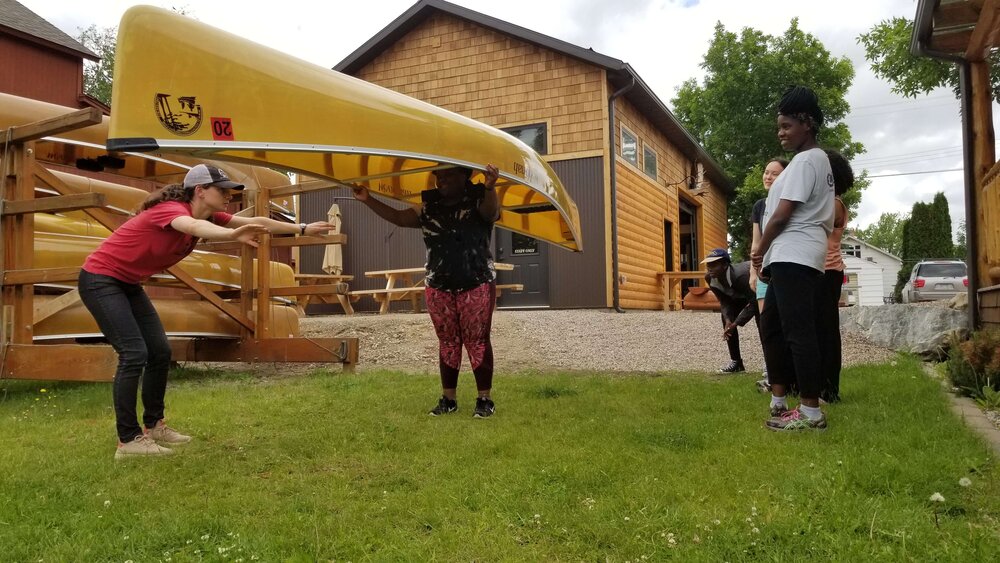 Woman practicing portaging a canoe at an outfitter.