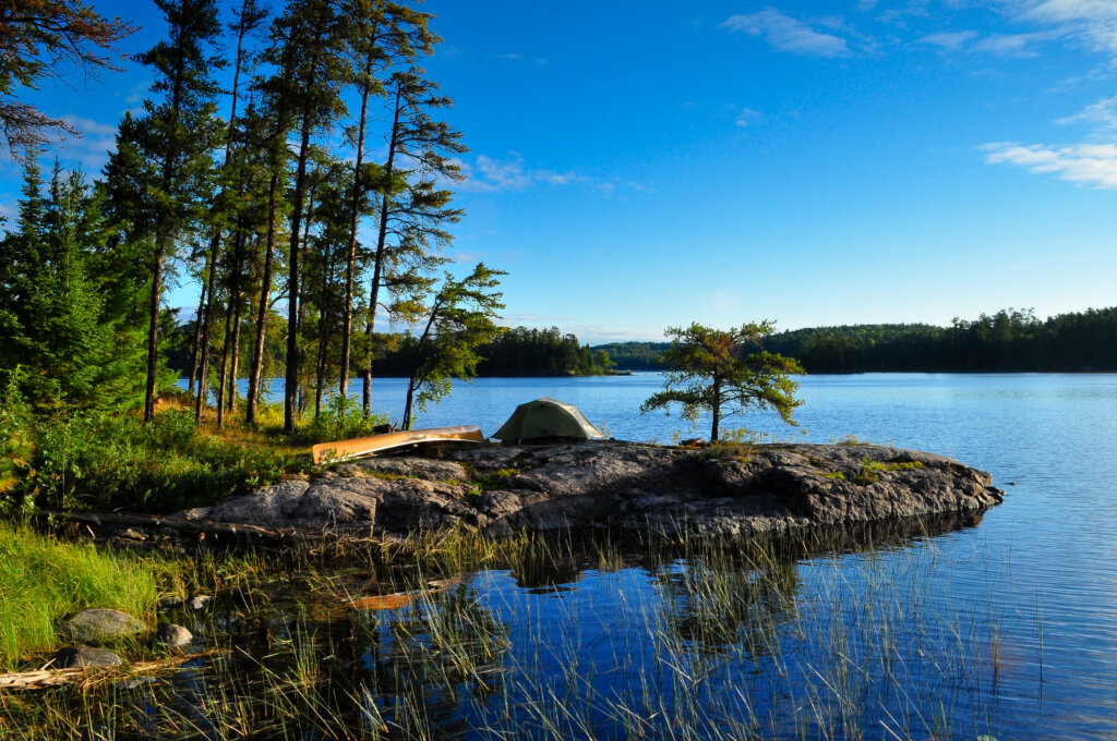 A canoe on a rock by some trees by the lake in the Boundary Waters